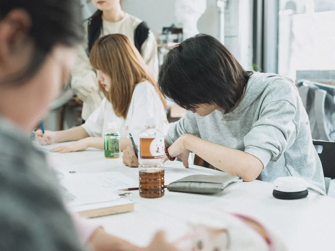 Students write at a long shared table in a Tokyo classroom